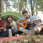 Trois amis jouent de la guitare en pleine nature