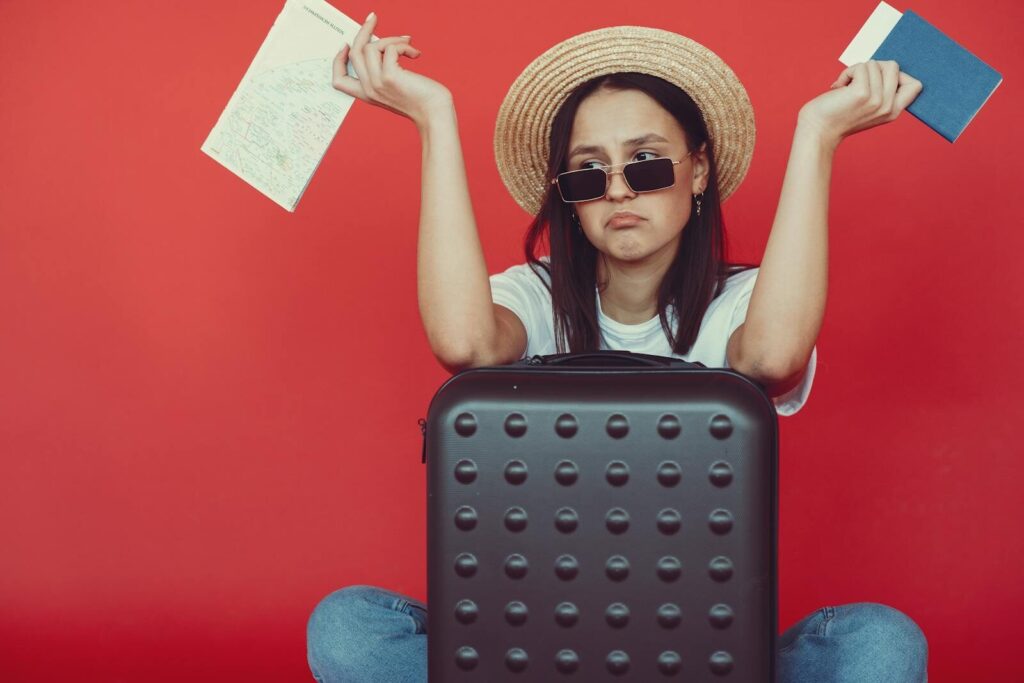 Femme assise sur une valise avec un chapeau